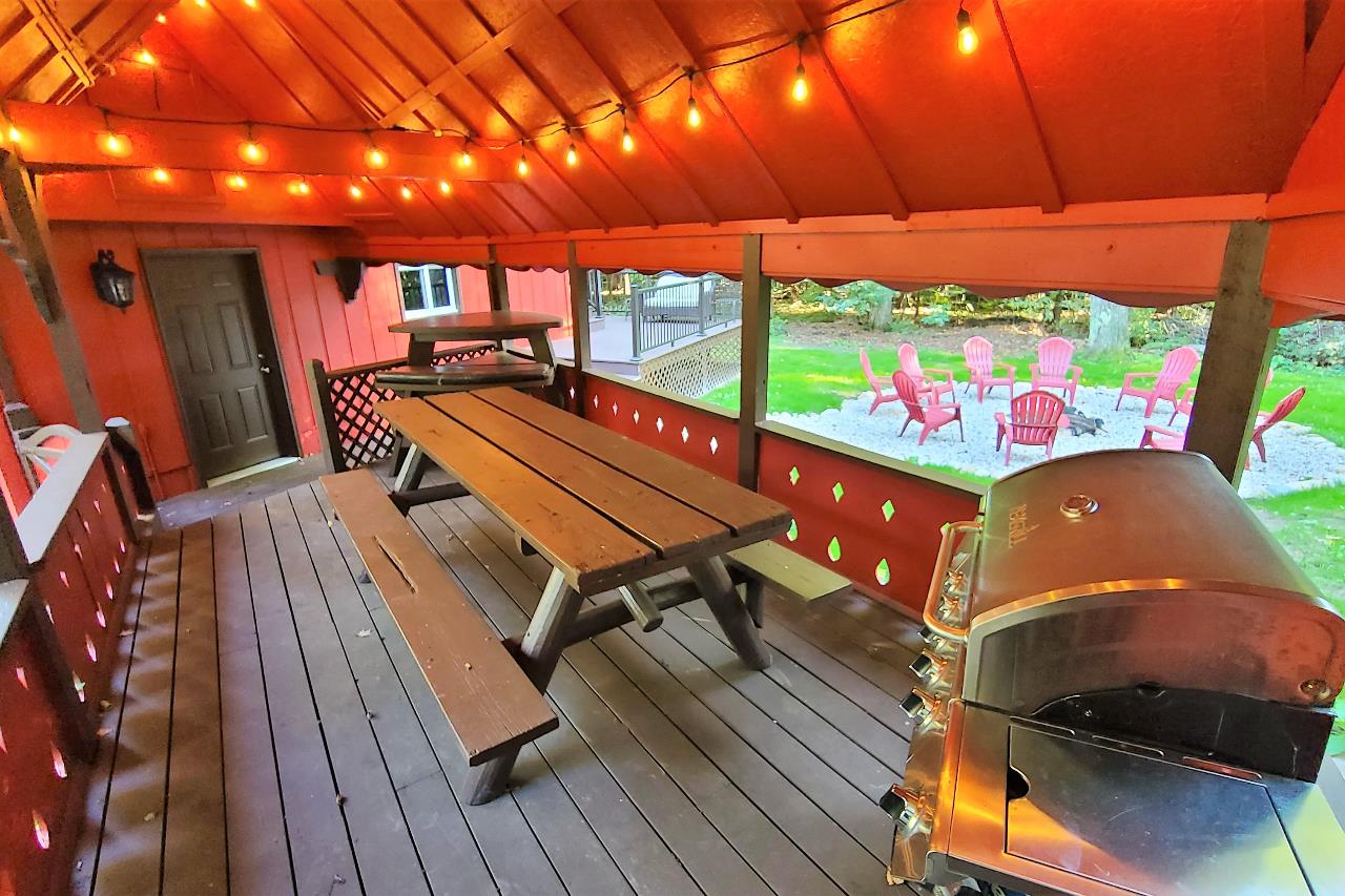 Covered breezeway between house and garage with gas grill and picnic table
